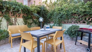 Une terrasse extérieure avec une table et des chaises, entourée de verdure et dotée d’un sol en pierre.