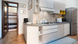 Une cuisine moderne équipée d’une cuisinière à gaz, d’un four à micro-ondes et d’un réfrigérateur en acier inoxydable.