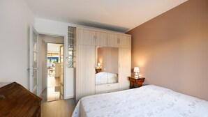 Un dormitorio con cama, armario, mesita de noche y cómoda de madera.