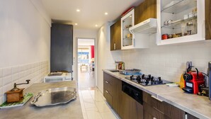 Una cocina moderna con estufa a gas, una cafetera roja y un horno empotrado.
