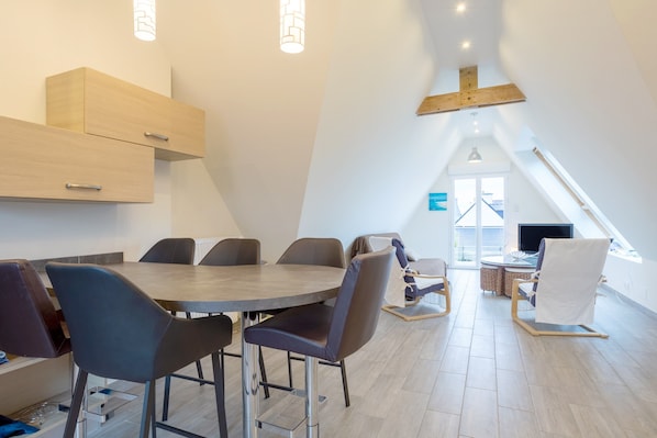 Un espace repas moderne avec une table ronde, plusieurs chaises et des meubles de rangement en bois intégrés.