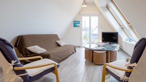 Een moderne loft slaapkamer met een bed, twee stoelen, een televisie en een eettafel.
