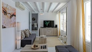 A modern living room with a sofa, coffee table, and a TV. - Villa "Harmony' with Sea View, Private Pool & Wi-Fi (Mykonos)