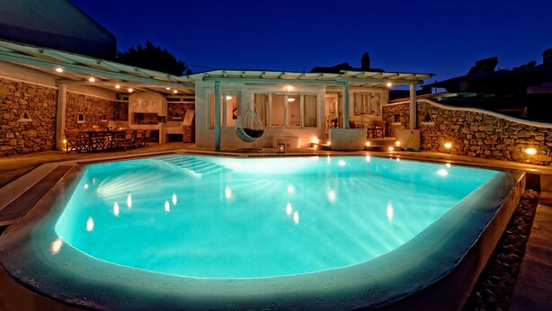A swimming pool with a stone wall and a covered seating area. - Villa "Harmony' with Sea View, Private Pool & Wi-Fi (Mykonos)