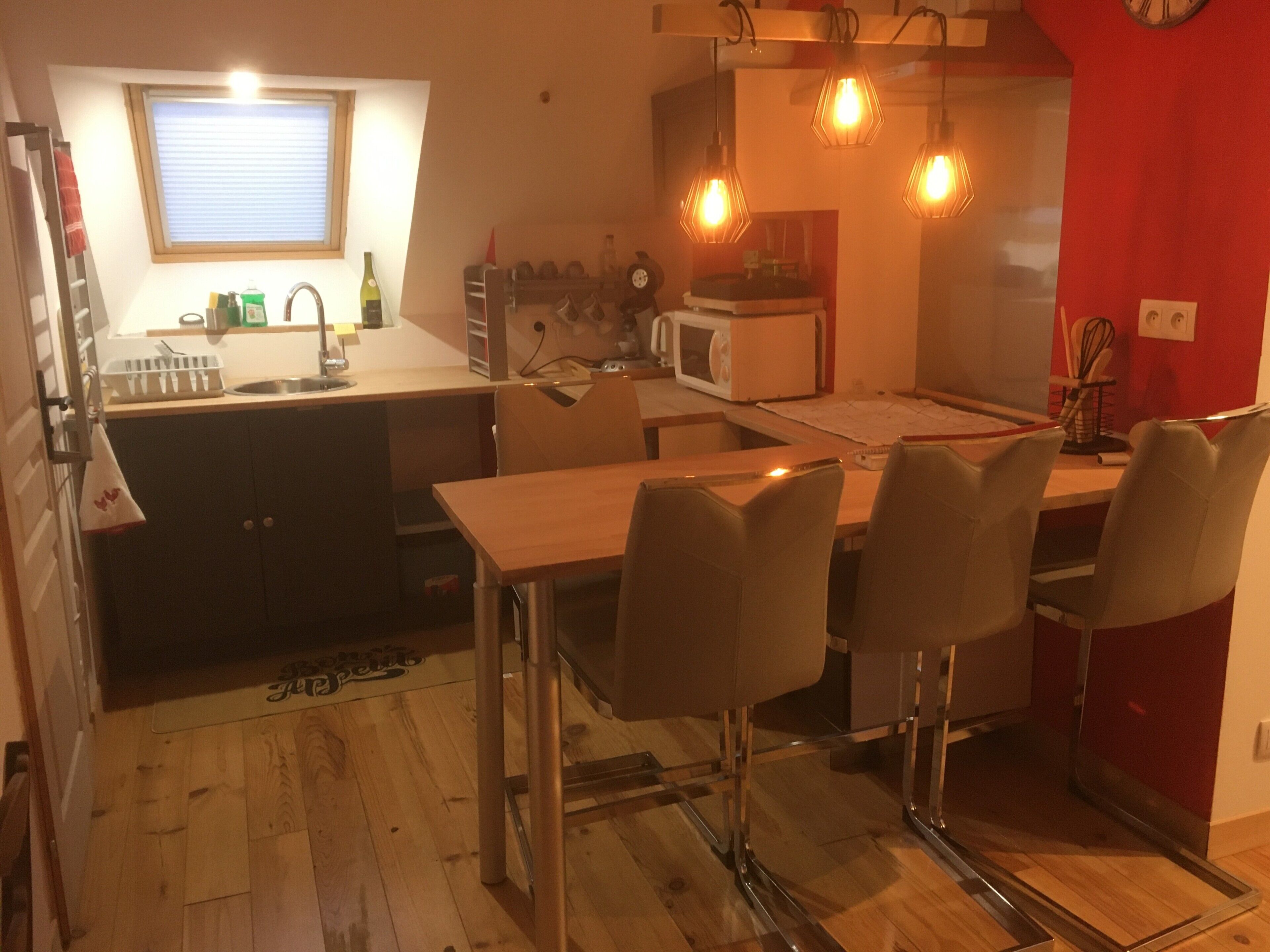 Une cuisine compacte avec un coin repas, un four à micro-ondes et un mur d’accent de couleur rouge.