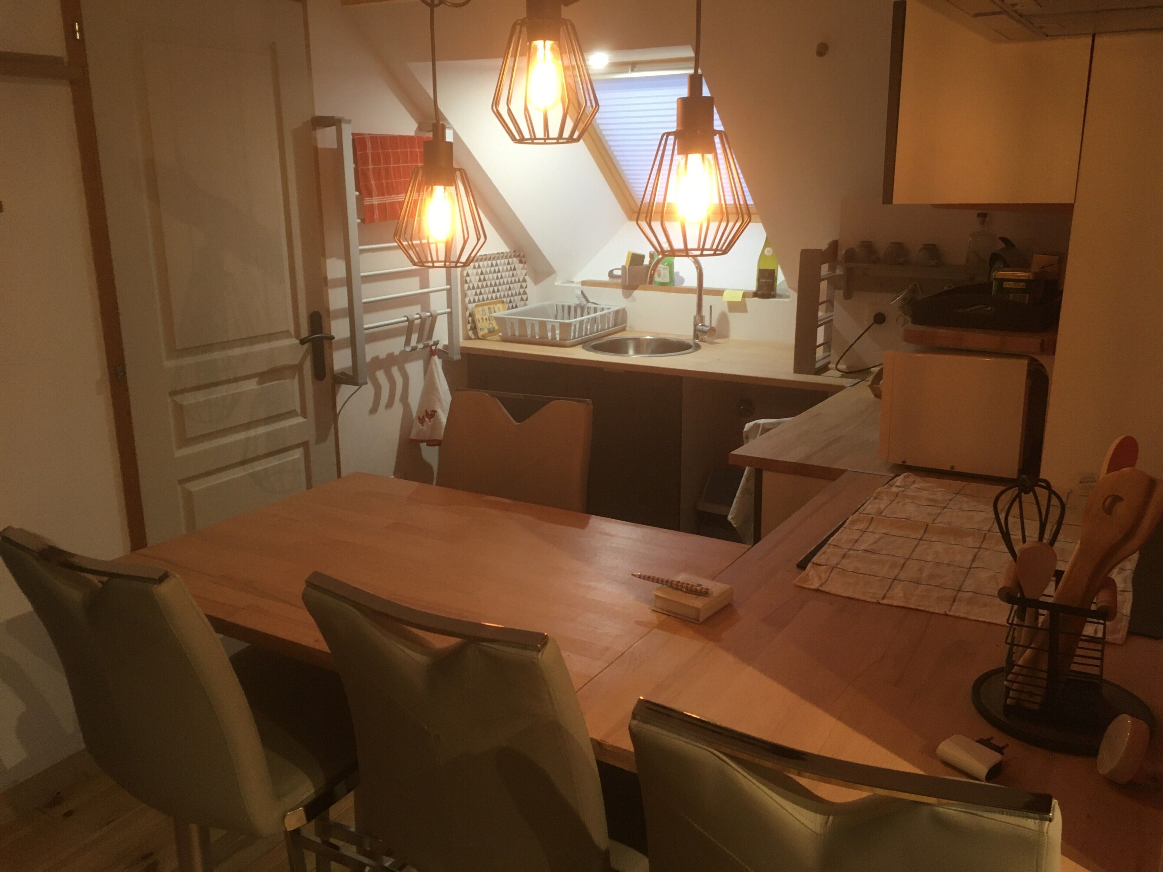 Un comedor con mesa de madera, cuatro sillas y lámparas colgantes.