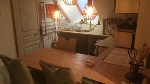 A dining area with a wooden table, four chairs, and pendant lights.