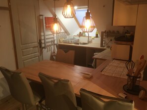 A dining area with a wooden table, four chairs, and pendant lights.