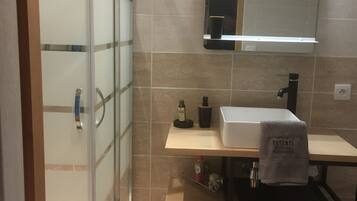 Une salle de bain moderne avec une douche à parois de verre, un lavabo avec une serviette et un miroir au-dessus du plan de travail.