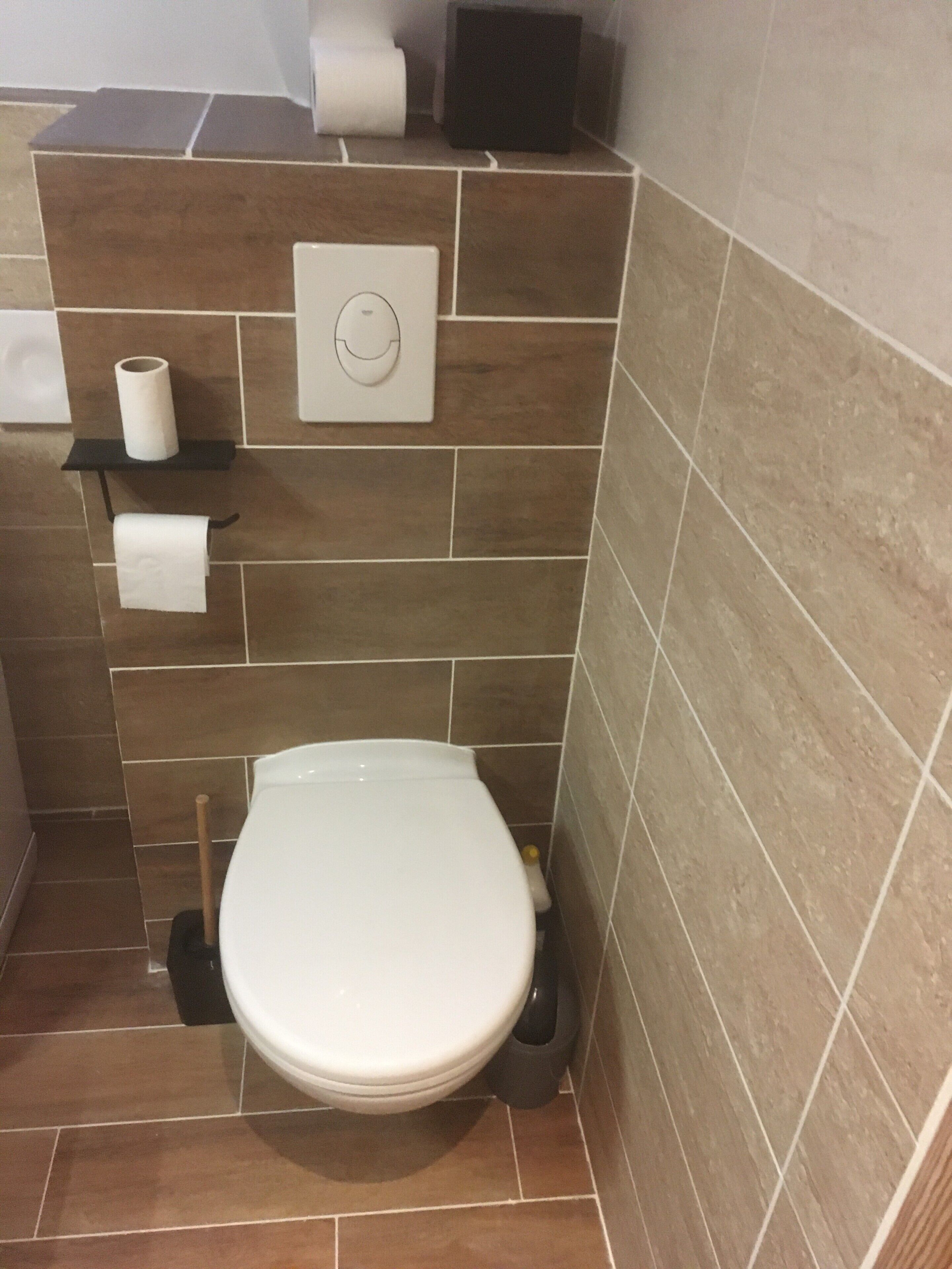 Et badeværelse med toilet, toiletpapirholder og bidét.