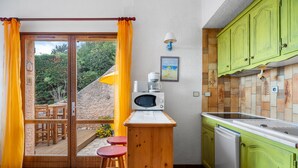 Une cuisine équipée d’un four à micro-ondes, d’un évier et de meubles de couleur verte.