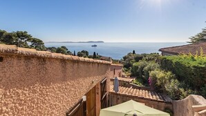 Une vue sur la côte, avec un bâtiment doté d’un toit de chaume et de tuiles en terre cuite, qui surplombe la mer.