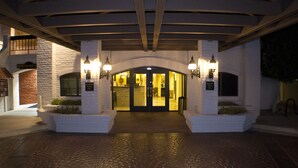 Ein Hotel mit einer Steinfassade, einem überdachten Eingangsbereich und zwei Wandleuchten.