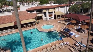 Ein Poolbereich mit mehreren Schwimmbecken, Liegestühlen und Sonnenschirmen.