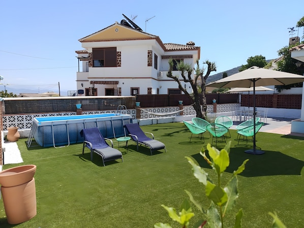 Ein Pool mit Liegestühlen, ein weißes Gebäude mit Balkon und Blick aufs Meer.