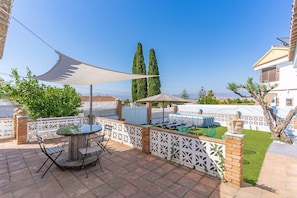 Une terrasse avec une table et des chaises, un espace salon abrité et une vue sur le paysage.