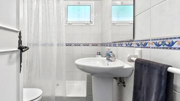 Une salle de bain avec un lavabo blanc, des toilettes, un rideau de douche et un porte-serviettes.