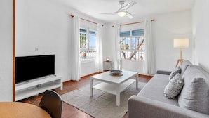 A living room with a flat-screen TV, a white coffee table, a grey sofa, and a ceiling fan. - Villa Namasté with Pool, Terraces, Near Beaches and Málaga Airport (Alhaurin de la Torre)
