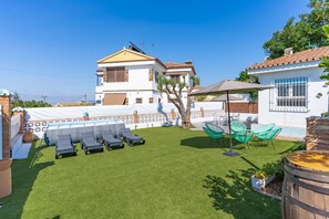 Um quintal com piscina, cadeiras de descanso e uma pérgula.
