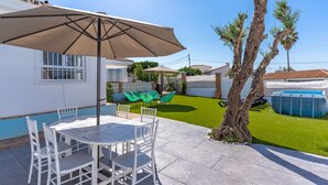 A patio with a table and chairs, a covered umbrella, a swimming pool, and a well-maintained lawn. - Villa Namasté with Pool, Terraces, Near Beaches and Málaga Airport (Alhaurin de la Torre)