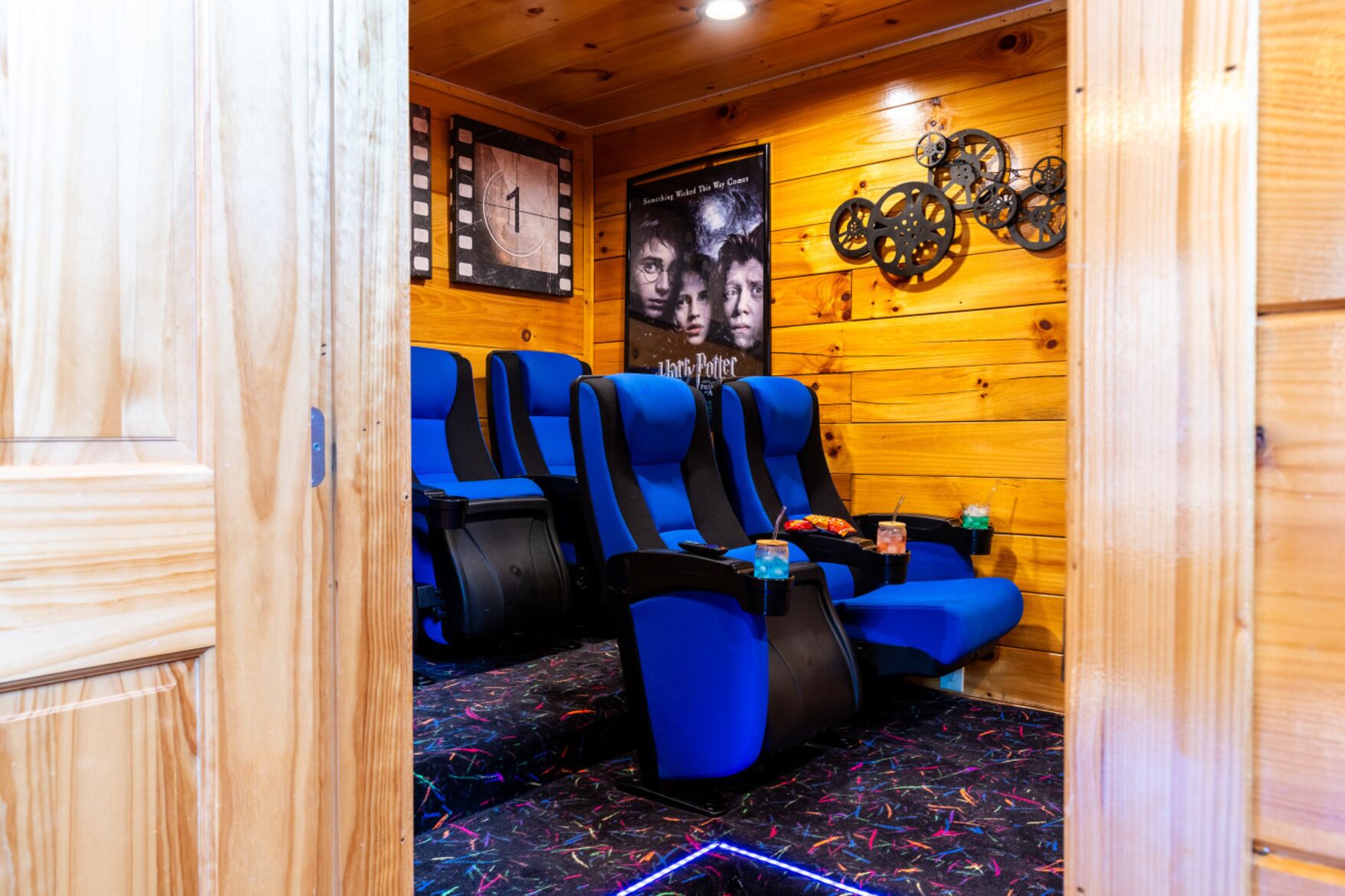 A room with wooden walls, a poster of a movie, and blue chairs with a black seat cushion.