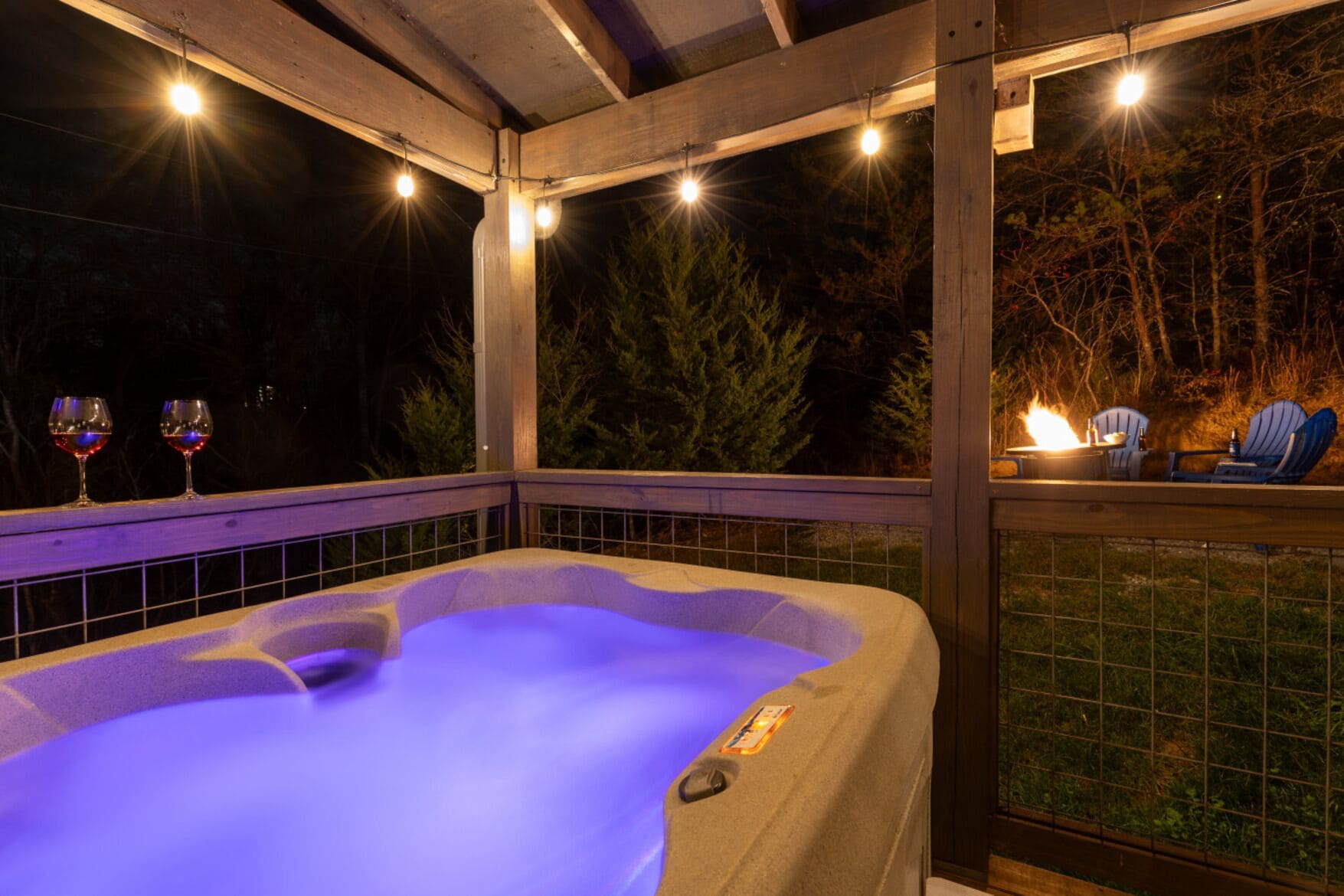 A hot tub with a wooden deck and a view of trees.