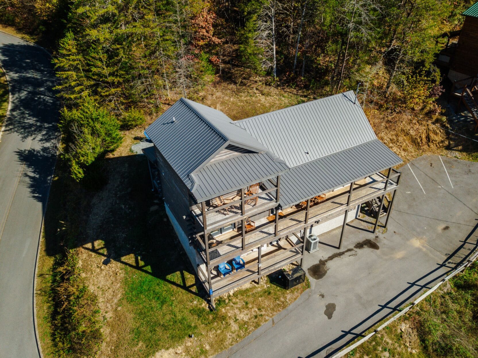 A two-story building with a metal roof, a covered outdoor seating area, and a paved parking area.