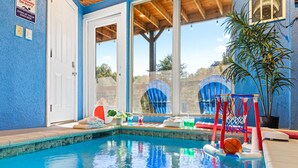 An indoor swimming pool with clear blue water, a basketball hoop, and a view of the outdoors through large windows. - Family Oasis By Ghosal Luxury Lodging (Sevierville)
