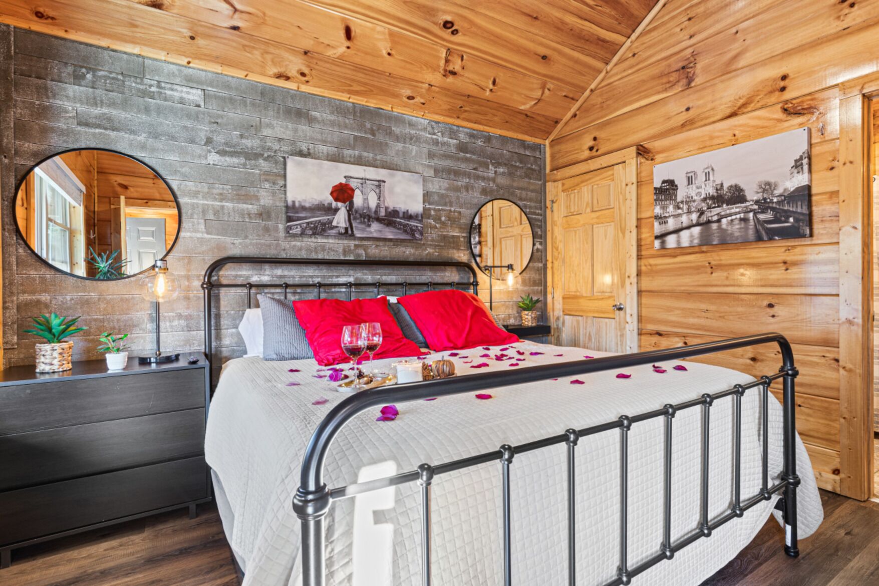 A wooden cabin-style bedroom with a bed, two round mirrors, and a wooden door.