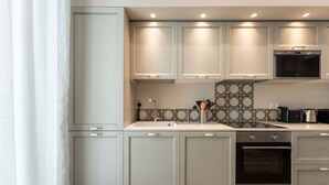 Et moderne køkken med hvide skabe, et mønstret backsplash og integrerede hårde hvidevarer.