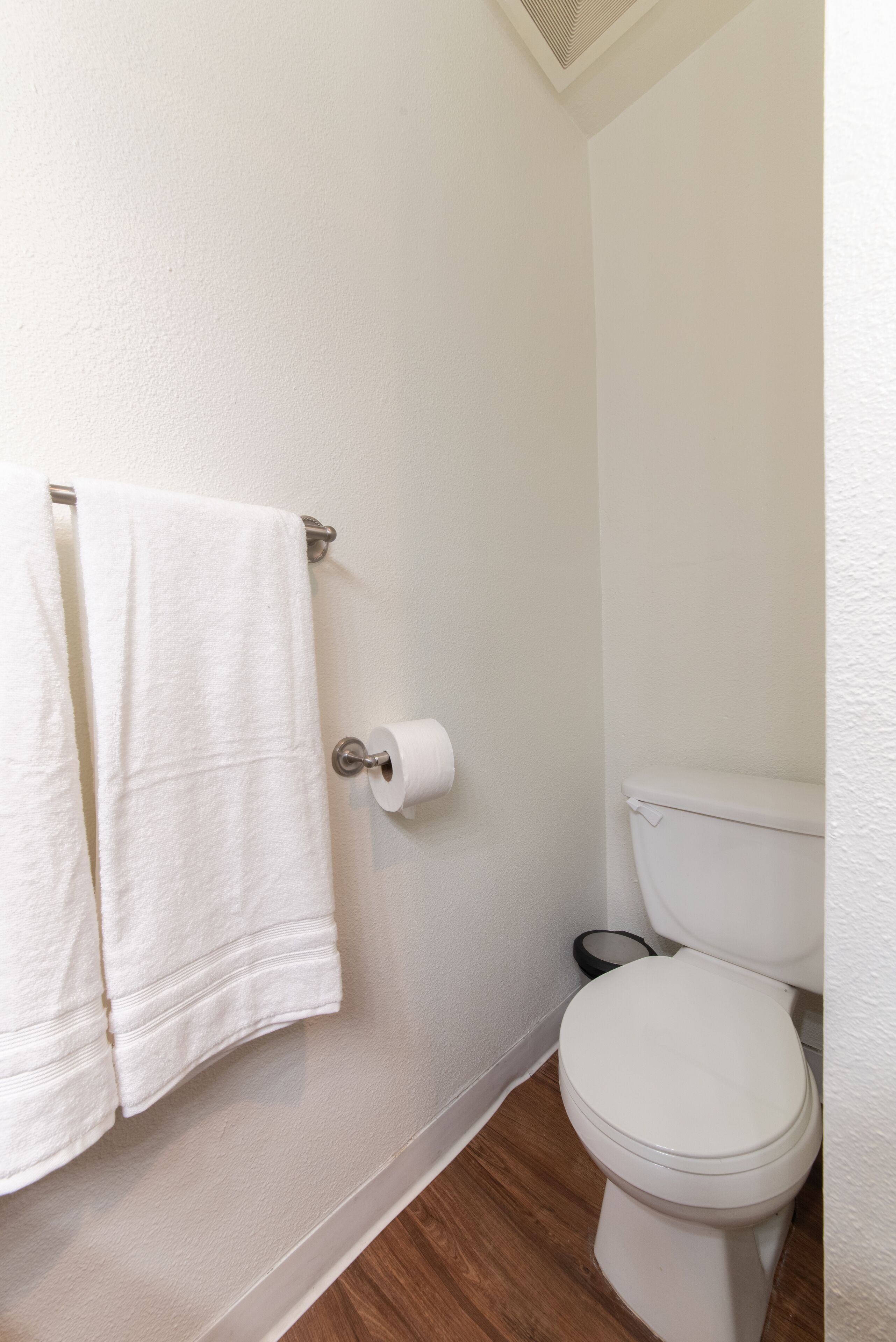 Une salle de bain avec des toilettes, un rouleau de papier toilette et deux serviettes suspendues à un porte-serviettes.