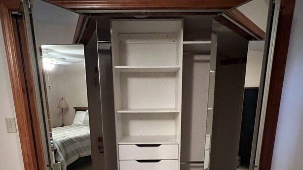 Ein Zimmer mit einem Schrank mit Spiegel, einem Bett und einer Lampe.