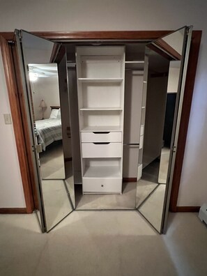 Ein Zimmer mit einem Schrank mit Spiegel, einem Bett und einer Lampe.