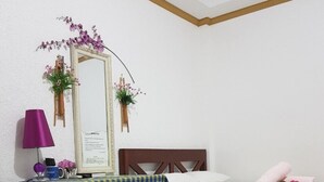 Quarto de hotel com duas camas, um espelho, uma luminária e flores decorativas.