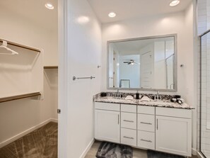 A modern bathroom with a double vanity, white cabinets, a granite countertop, and a large mirror. - Atlantis (Tolleson)