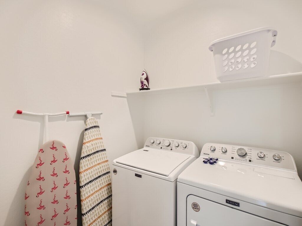 A laundry area with two washing machines and a drying rack.