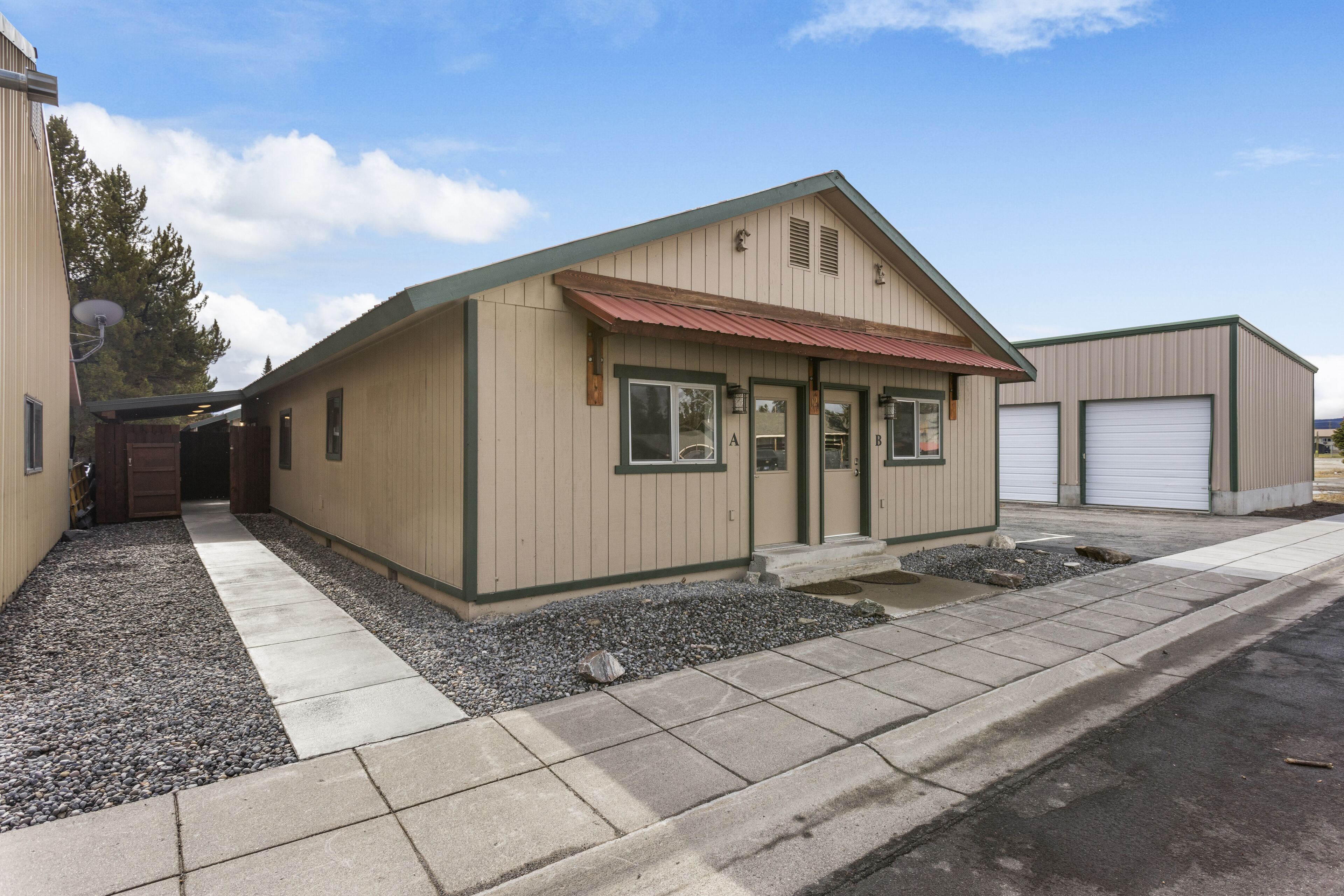 A single-story building with a red roof, beige walls, and a gravel driveway.