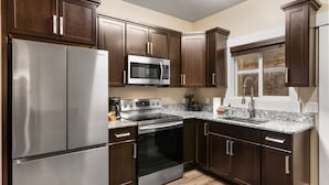 A modern kitchen with stainless steel appliances, dark wood cabinets, and granite countertops. - The Yellowstone Hideaway Unit C (West Yellowstone)