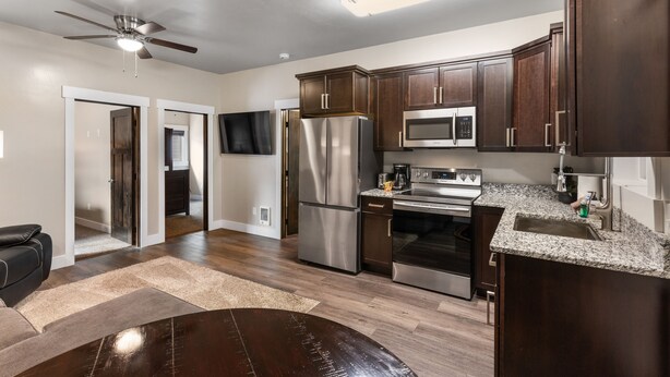A modern kitchen with dark wood cabinets, stainless steel appliances, and a granite countertop. - The Yellowstone Hideaway Unit C (West Yellowstone)