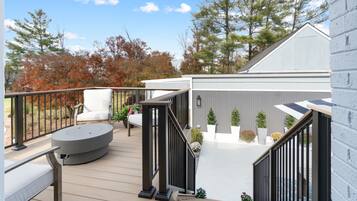 A deck with outdoor furniture, a staircase, and a building in the background.