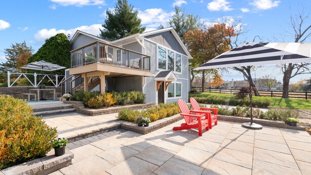 Une maison moderne dotée d’un patio couvert, d’un espace salon extérieur et offrant une vue sur le paysage environnant.