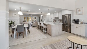 Une cuisine moderne avec des armoires blanches, des appareils en acier inoxydable et des luminaires suspendus.