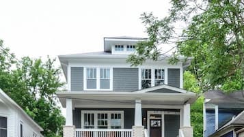 A two-story house with a front porch, a garage, and a visible address sign.