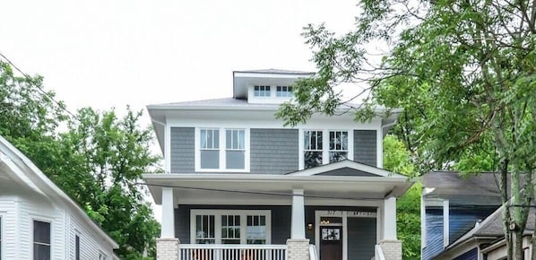 A two-story house with a front porch, a garage, and a visible address sign.