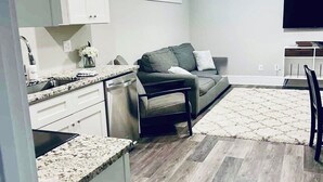 Una cocina moderna con armarios blancos, encimera de granito y lavavajillas integrado.
