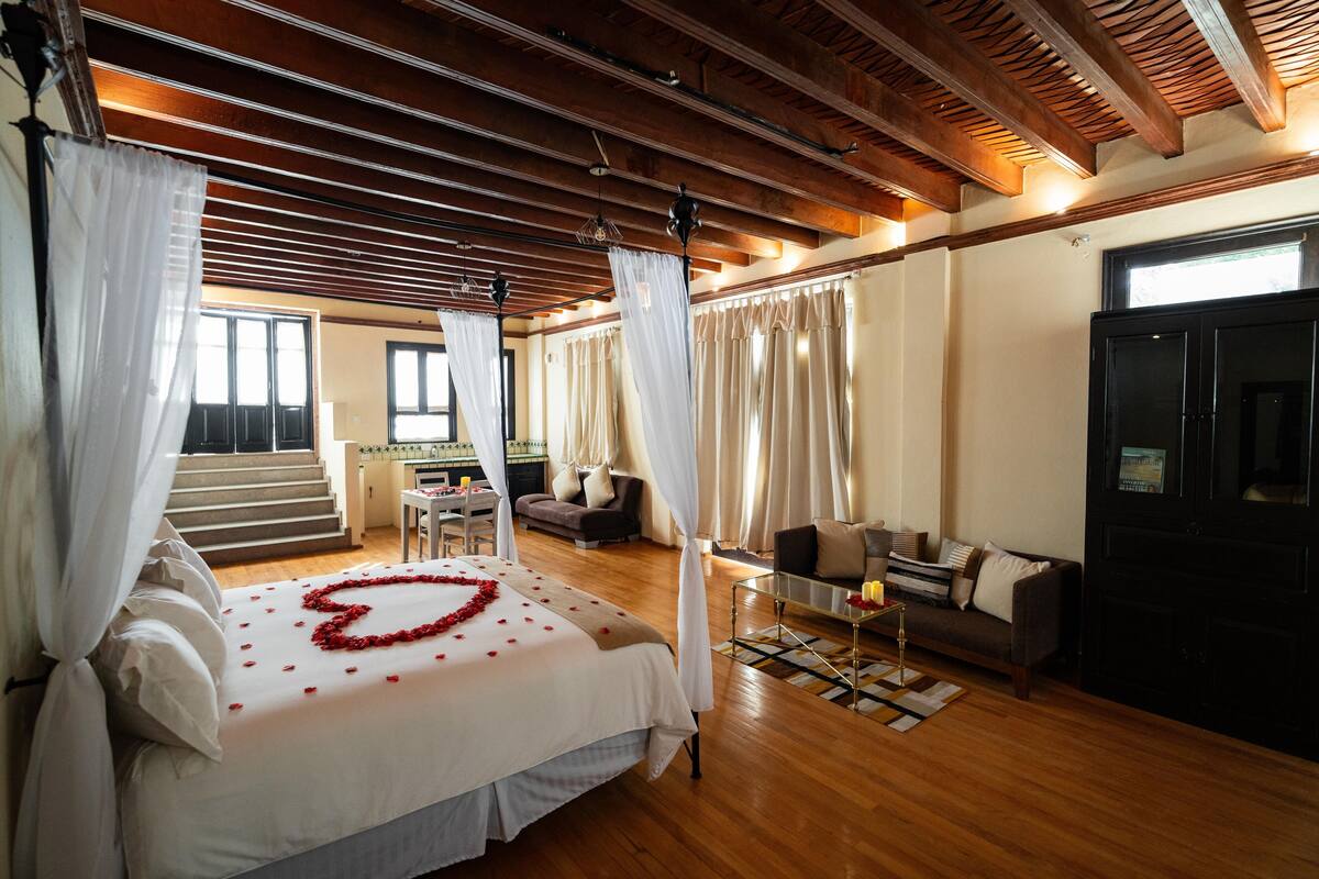 A bedroom with a bed, a sofa, a coffee table, and a TV.