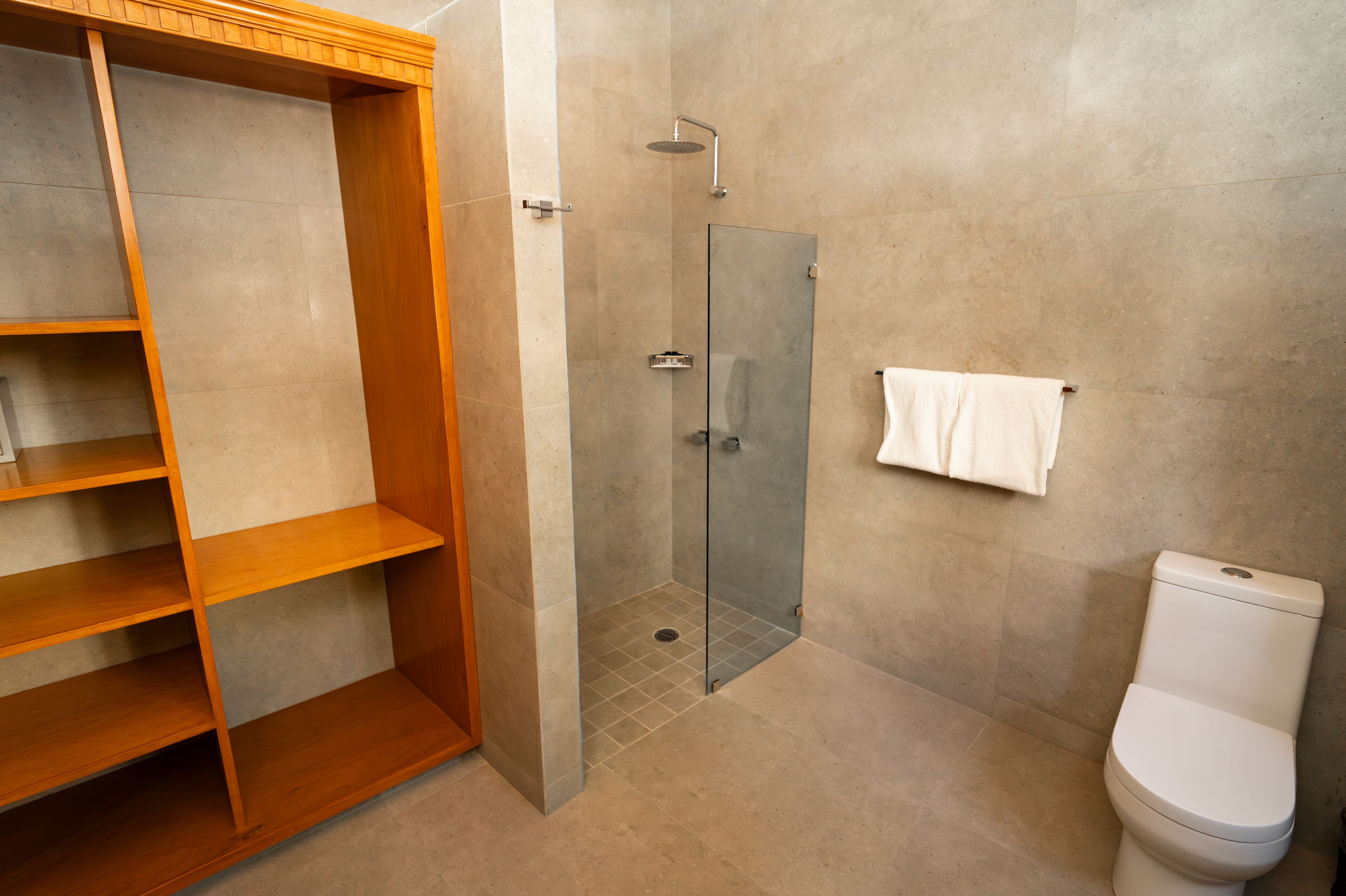 Ein modernes Badezimmer mit Duschkabine aus Glas, einer Holzeinrichtung und einer weißen Toilette.