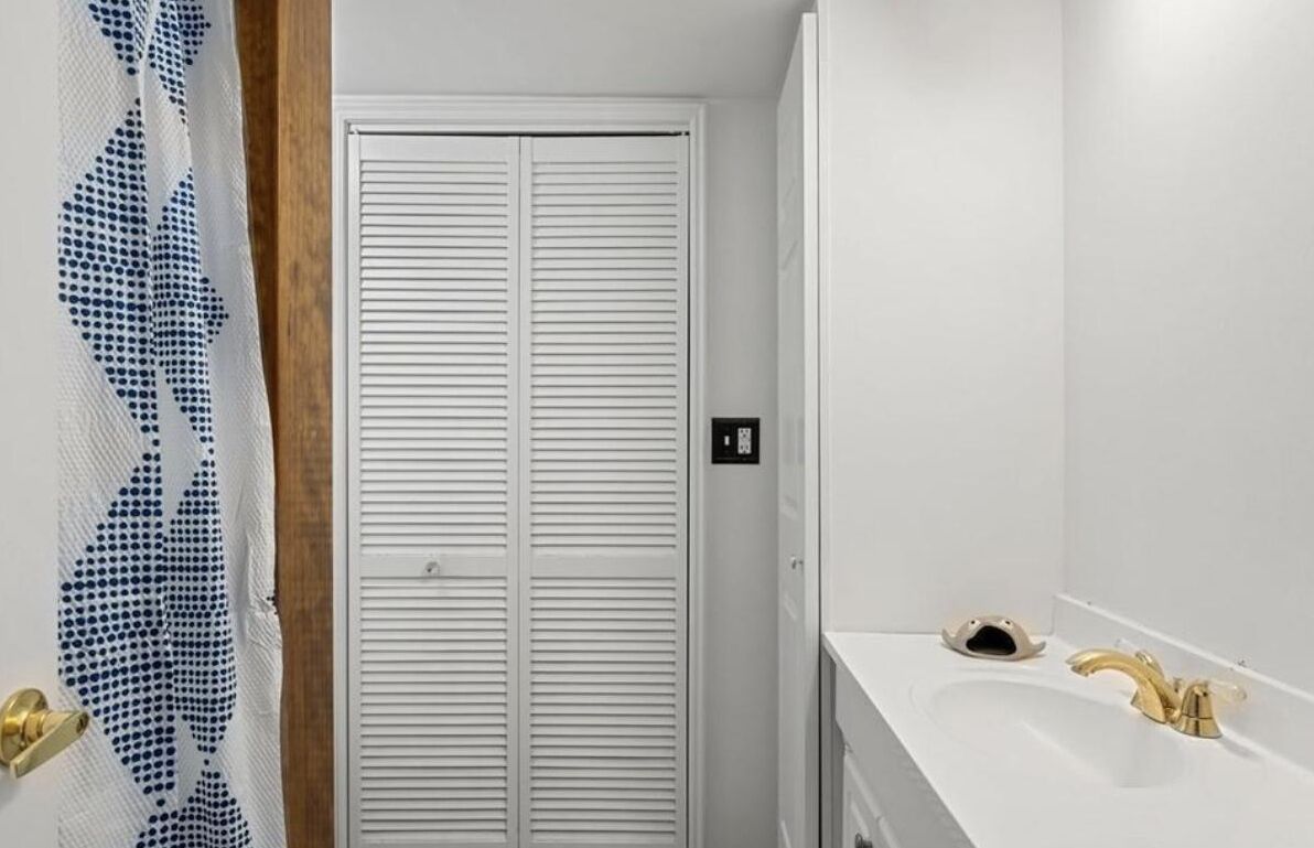 Une salle de bain avec un lavabo blanc, un robinet doré et des toilettes blanches.