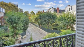 A courtyard with a cobblestone path, surrounded by lush greenery and traditional buildings.