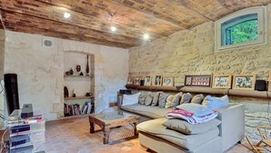 A cozy living room with a stone wall, a sofa, a coffee table, and a bookshelf.
